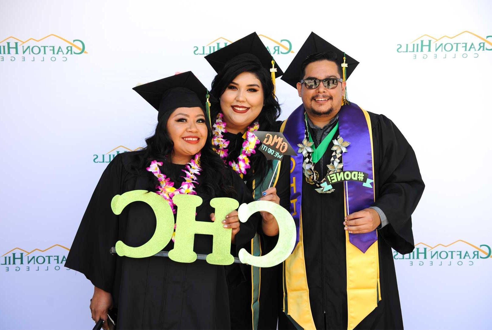 Students holding CHC lettering, wearing regalia